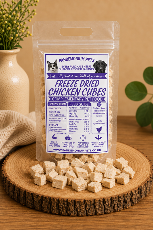 Freeze Dried Chicken Cubes 50g bag on a wooden board with chicken cubes scattered around it
