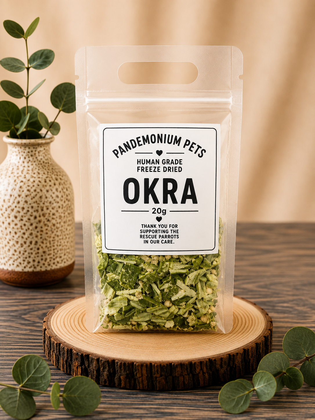 Pandemonium Pets Human Grade Freeze Dried Okra 20g in a clear resealable pouch on a wooden slice